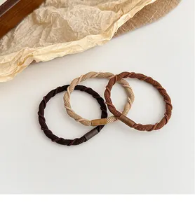 Detailed view of elastic spiral hair ties in earth tones with leather accents