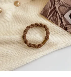 Dettaglio dell'elastico per capelli intrecciato marrone ad alta elasticità su tessuto a maglia