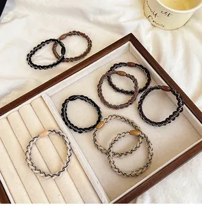 Detailed shot of woven elastic hair ties in earth tones on a soft velvet display tray