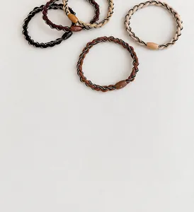 Close-up of five woven elastic hair ties in neutral tones with resin accents