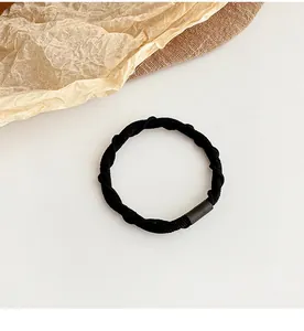 Close-up of black elastic hair tie with spiral texture and matte connection sleeve