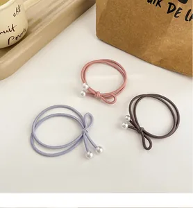 Vue détaillée de trois élastiques à cheveux avec perles en tons rose, bleu et marron