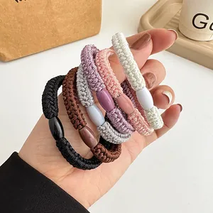 Handgehaltenes Set aus dicken, gewebten elastischen Haargummis in sechs Farben