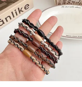 Detail of five elastic woven hair ties in earth tones with decorative round beads
