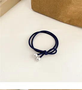 Détail d'un élastique à cheveux bleu marine avec nœud élégant et perles blanches