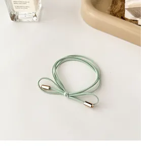 Detail of light green bow hair tie with golden metal tips on a clean background