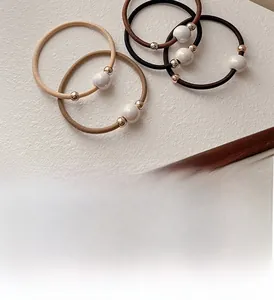 Detail of five high-elasticity hair ties with pearl beads and gold rings in neutral tones
