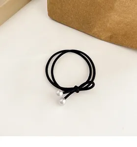 Détail d'un élastique à cheveux noir double rang orné de deux perles blanches