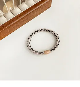 Detailed view of contrast color braided high elastic hair tie with a smooth beige bead