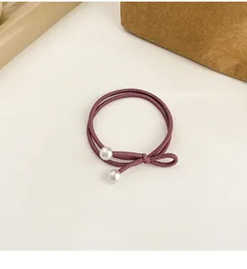 Détail d'un élastique à cheveux double brin violet foncé avec perles blanches