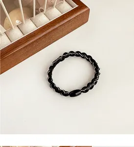 Macro detail of elastic woven hair tie with metallic thread and black connector bead