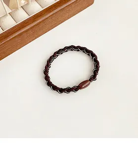 Macro detail of elastic woven hair tie with brown tones and resin connector