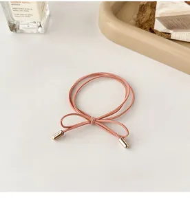 Close-up of pink double-strand elastic hair tie with gold metal caps in a bow shape