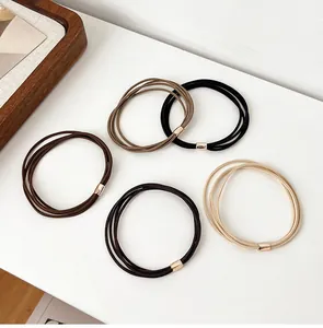 Detail of high-elastic multi-strand hair ties in neutral earth tones with gold metal clasps