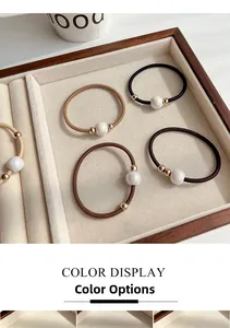 Close-up of elegant pearl hair ties in neutral earth tones on a velvet display tray
