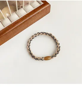 Close-up of beige and black woven elastic hair tie with a smooth brown resin bead detail
