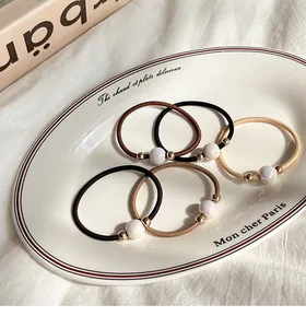 Close-up of high-elastic pearl hair ties in milk coffee shades on a ceramic tray