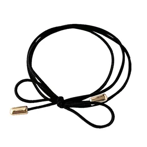 Elastic black bow hair tie with golden metal cylinders for girls' ponytail styling