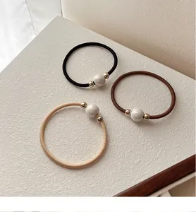 Detailed view of elastic hair ties in beige, coffee, and black with pearl accents