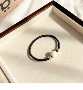 Close-up of high elasticity brown hair tie with elegant white pearl and gold metal beads