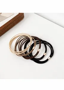 Detail view of elastic hair ties in neutral tones with gold metal clasps on white surface