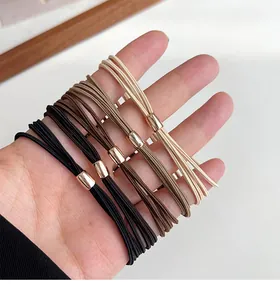Detail of four high-elastic hair ties in neutral earth tones with rose gold metal buckles
