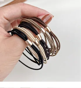 Detail of high-elasticity hair ties with gold metal buckles in earthy neutral tones