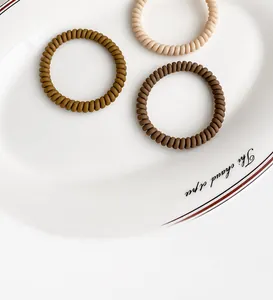 Close-up of three spiral hair ties in brown and beige tones on a white ceramic plate