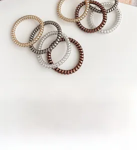 Macro detail of metallic spiral telephone wire hair ties in gold and silver tones