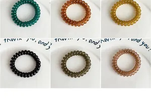 Macro view of jelly-colored spiral hair ties in six vibrant glossy finishes