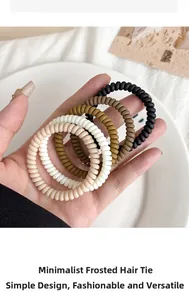 Close-up of five matte spiral hair coils in earth tones held in a hand for size