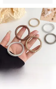 Close-up of metallic spiral hair ties in gold and silver shades held by a hand