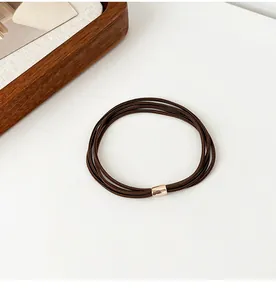 Detail of coffee brown elastic hair ties with a polished gold decorative metal buckle