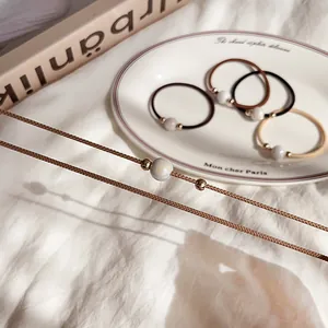 Elastic hair ties in earthy tones with lustrous pearl beads and gold accents