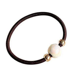 Minimalist elastic hair tie with dark brown band featuring iridescent pearl and gold beads
