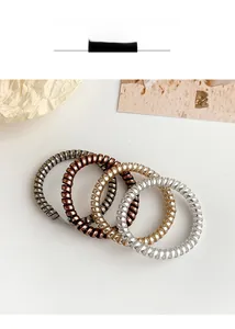 Macro detail of metallic spiral telephone wire hair ties in gold and silver finishes