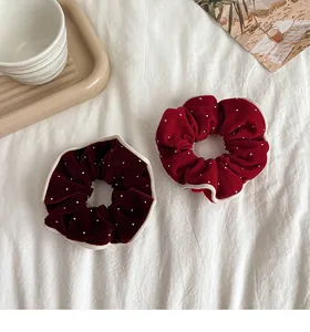 Close-up of velvet scrunchies with wavy edges and rhinestones on a decorative tray