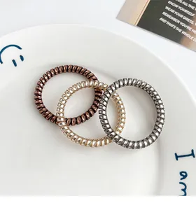 Detailed macro view of metallic spiral hair ties in bronze and gold on a ceramic tray