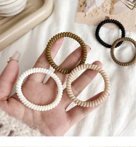 Macro shot of matte neutral toned spiral hair ties in white, beige and brown