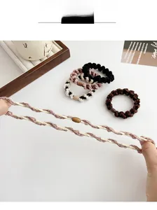 Détail d'élastiques à cheveux tressés avec perles en bois montrant une grande élasticité