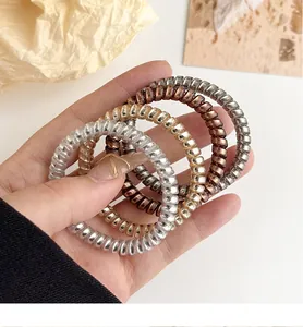 Detail view of four metallic spiral hair ties in gold, silver, and bronze finishes