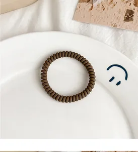 Close-up of a matte brown spiral hair tie in a ceramic tray with soft lighting
