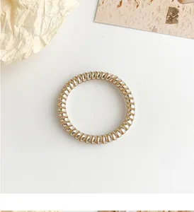 Macro shot of a champagne gold spiral telephone wire hair tie with metallic luster