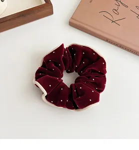 Detail of burgundy velvet scrunchie with white beads and elegant cream piping trim