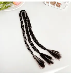 Détail d'une extension tressée grise et noire avec élastique sur un bureau minimaliste