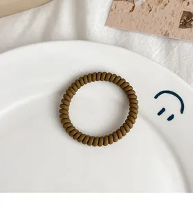 Detailed macro view of a matte brown spiral hair tie resting on a ceramic dish
