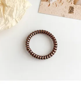 Macro shot of dark brown spiral phone cord hair tie with metallic glossy finish