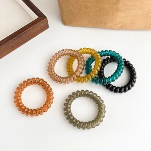 Set of 6 colorful spiral telephone wire hair ties in jelly colors on a white desk
