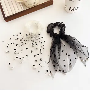 Dettaglio di elastici per capelli in tulle a cuori con fiocchi e perle decorative