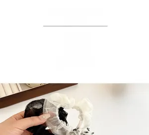 Dettaglio di eleganti elastici per capelli in mesh plissettato nero e bianco a pois